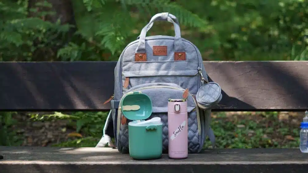 SmaFla 2.0 Babyflasche für unterwegs auf einer Parkbank neben einer Milchpulverbox.